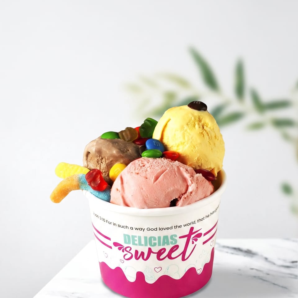 A cup of Delicias Sweet ice cream with chocolate, strawberry, and vanilla scoops, topped with candies.