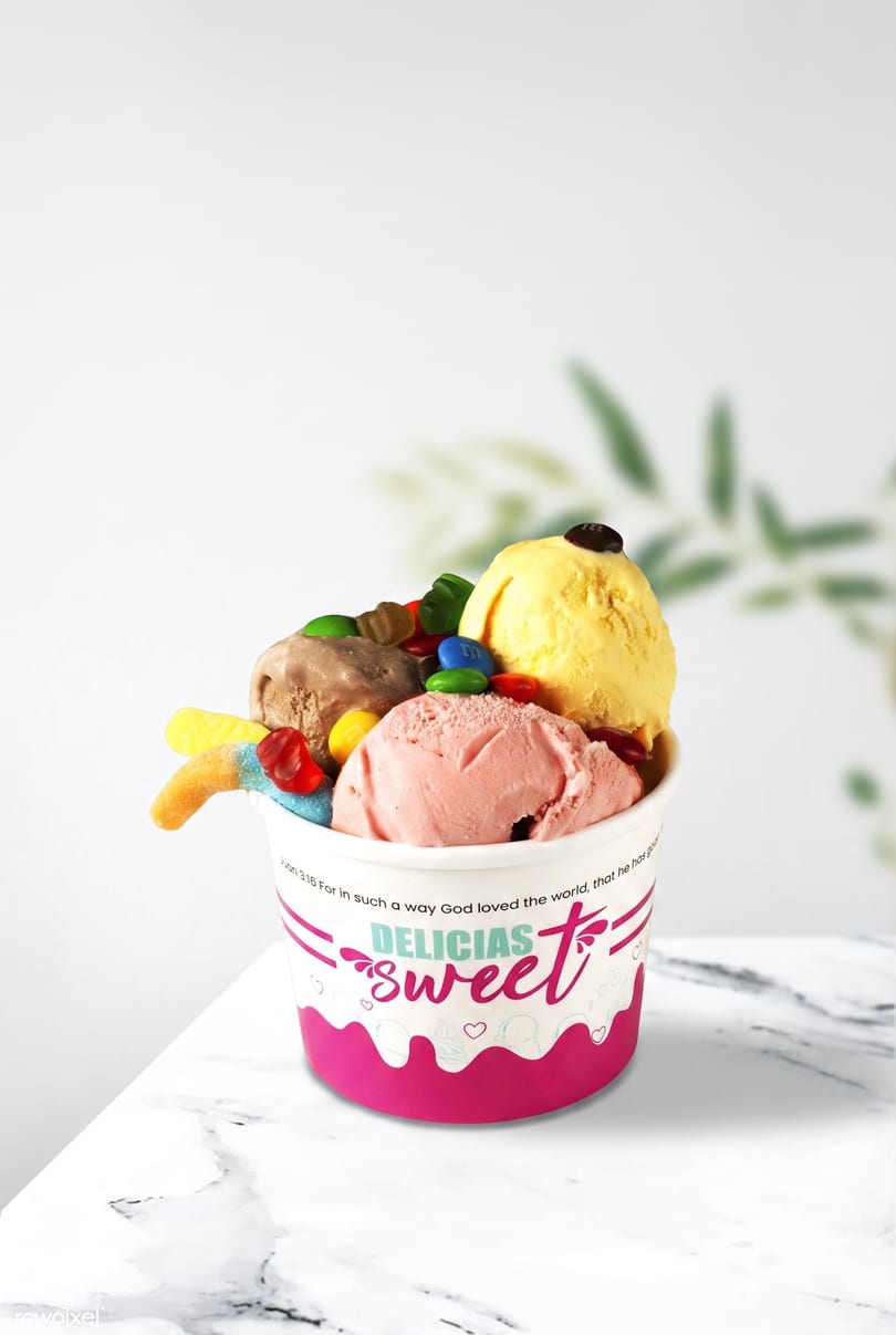 A cup of Delicias Sweet ice cream with chocolate, strawberry, and vanilla scoops, topped with candies.