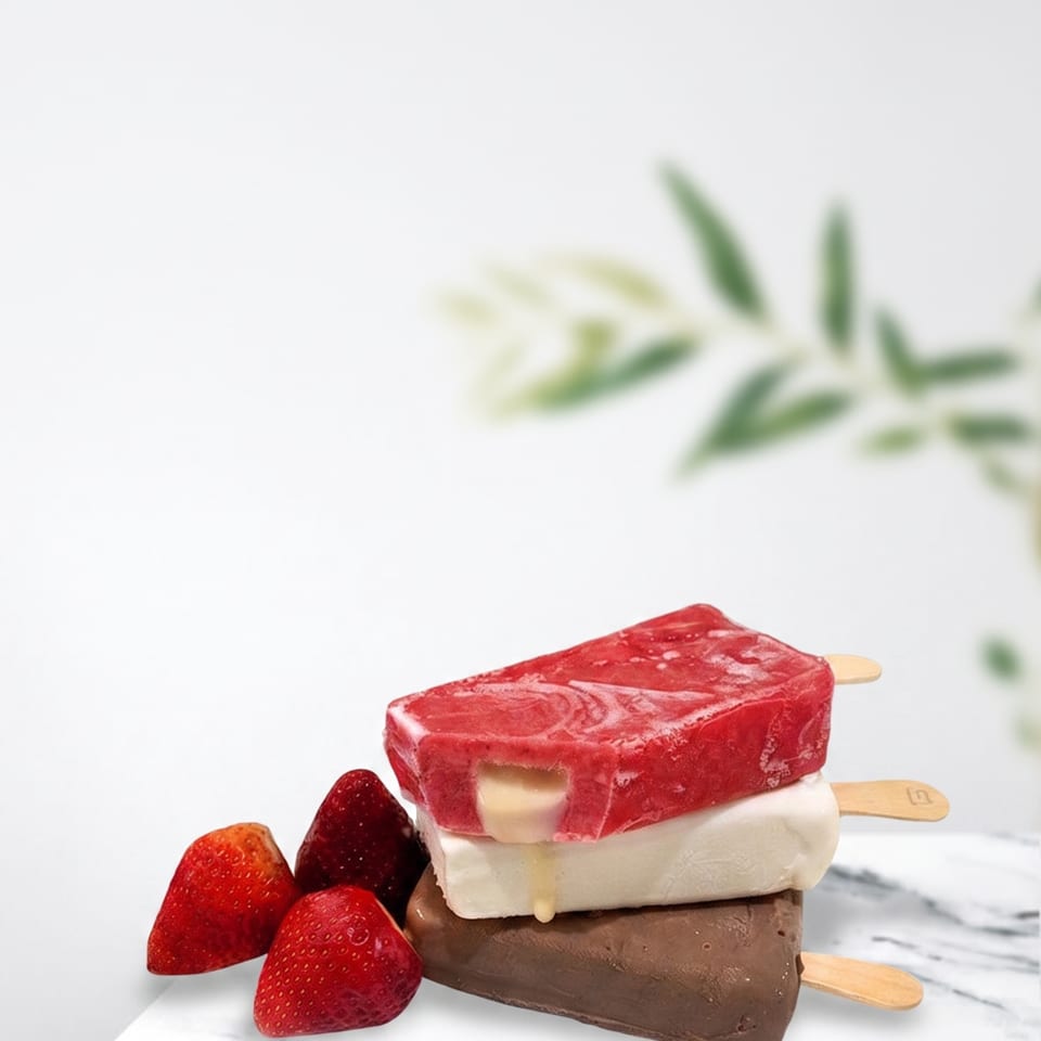 Stacked strawberry, vanilla, and chocolate popsicles with fresh strawberries on a marble surface.
